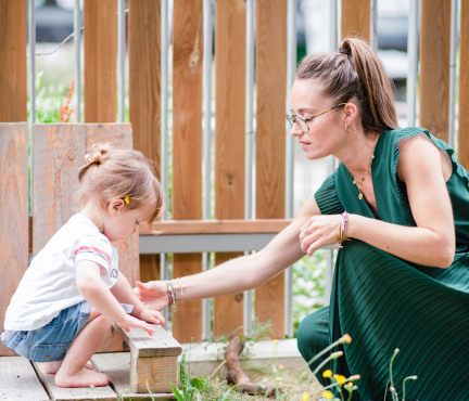 Une professionnelle de crèche avec un enfant dans un jardin