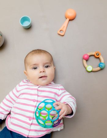 Un bébé allongé en crèche Babilou entouré de jouets
