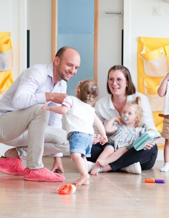 Un parent, une professionnelle et des enfants discutent en crèche Babilou