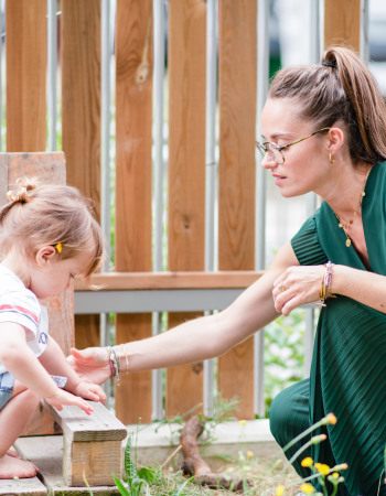 Une professionnelle de crèche avec un enfant dans un jardin