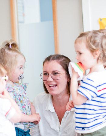 Professionnelle en crèche entourée d'enfant rigolant