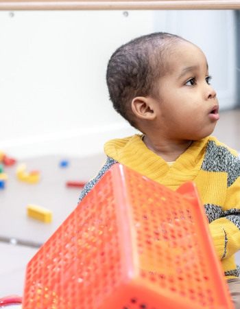 Un enfant assit entouré de jouets