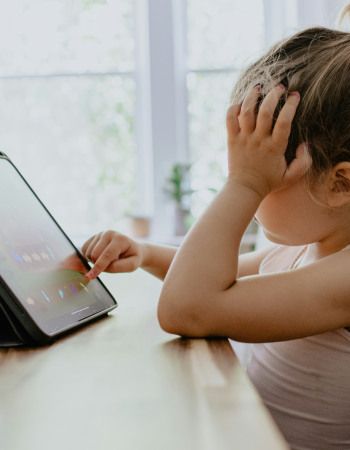 Un enfant sur une table en tain de jouer à la tablette