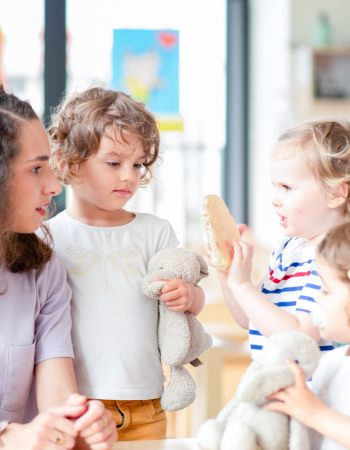 Professionnelle en crèche discutant avec un groupe d'enfants