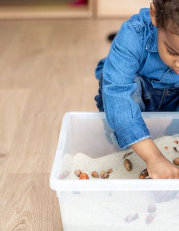Enfant en train de jouer avec un bac sensoriel
