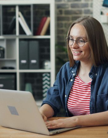 Un femme en train de travailler, souriante devant son ordinateur