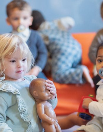 Deux petites filles jouant avec un groupe d'enfant au sein d'une crèche Babilou.
