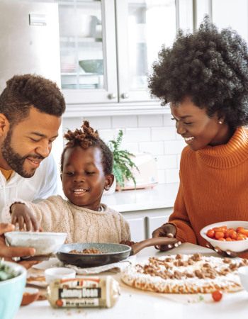 Deux parents et un enfant, qui cuisinent à la maison