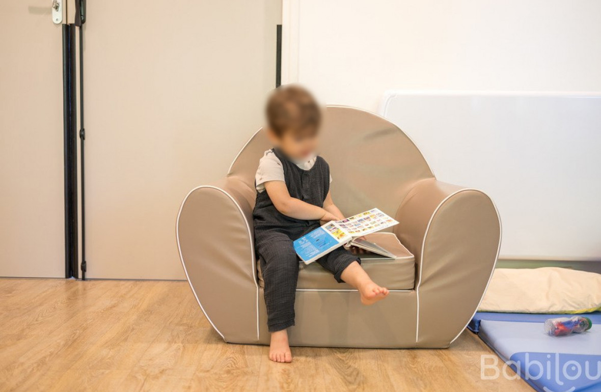 Un enfant lit un livre sur un siège.