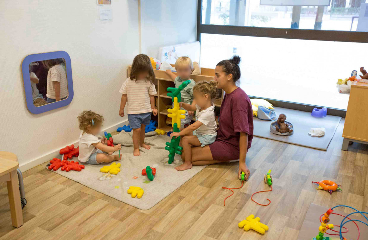 Une professionnelle en crèche jouant avec un groupe d'enfant 