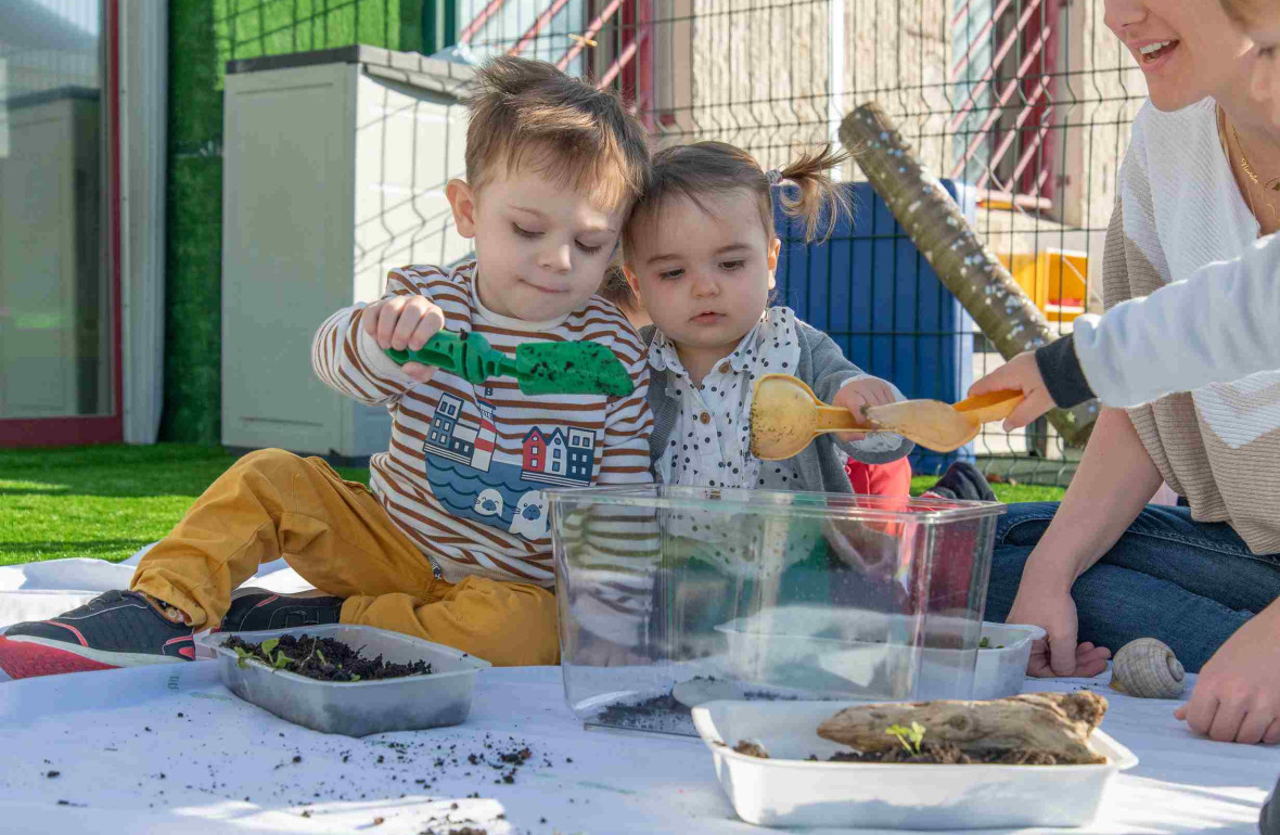 Deux enfants et une pro dans le jardin en interaction 