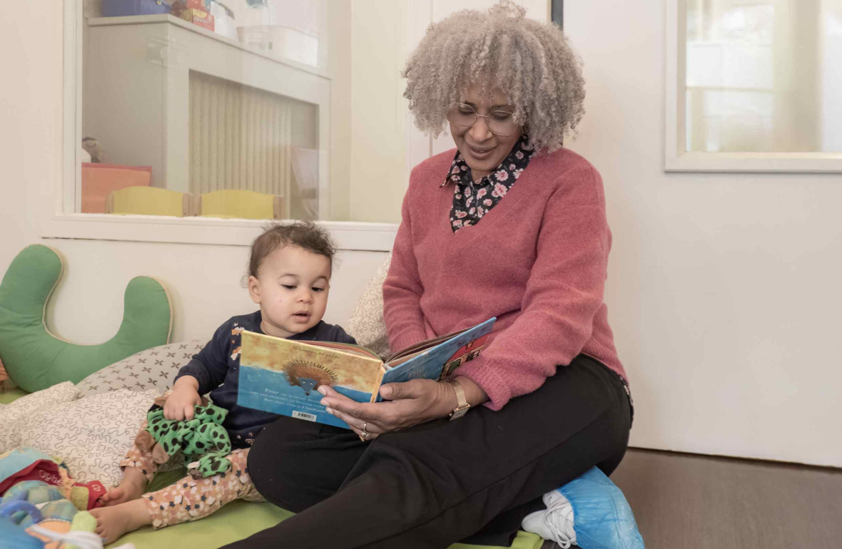 Une pro en crèche qui lit un livre à un enfant