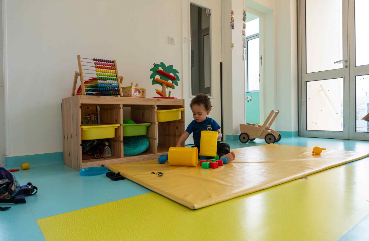 Un enfant en crèche qui joue sur un tapis d'éveil