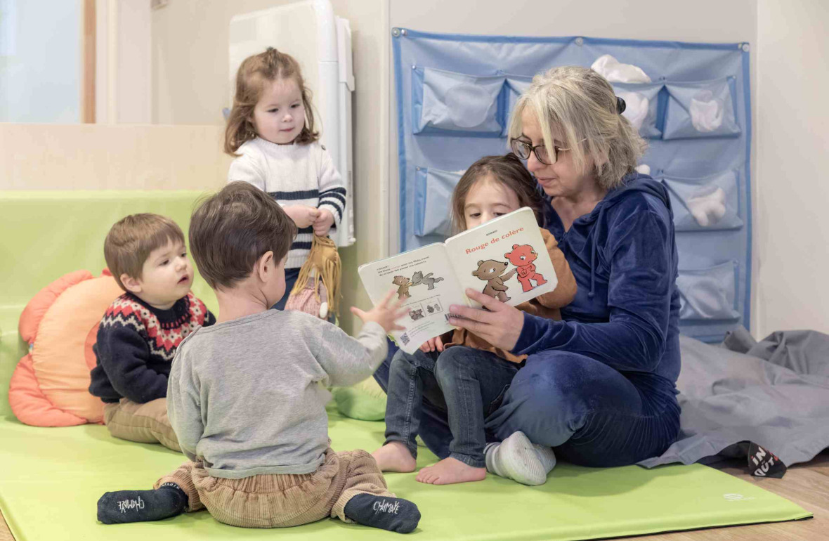 Une pro qui lit un livre à un groupe d'enfant en crèche 