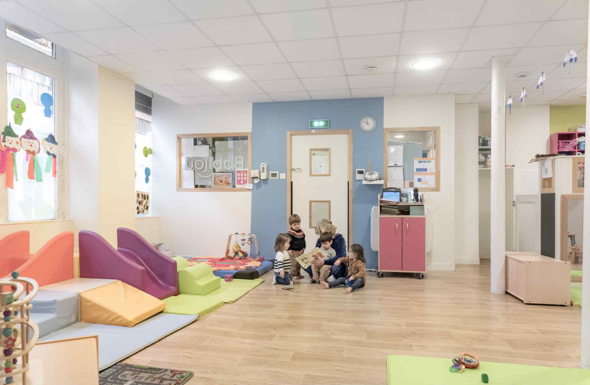 Une pro en crèche en interaction avec deux enfants 