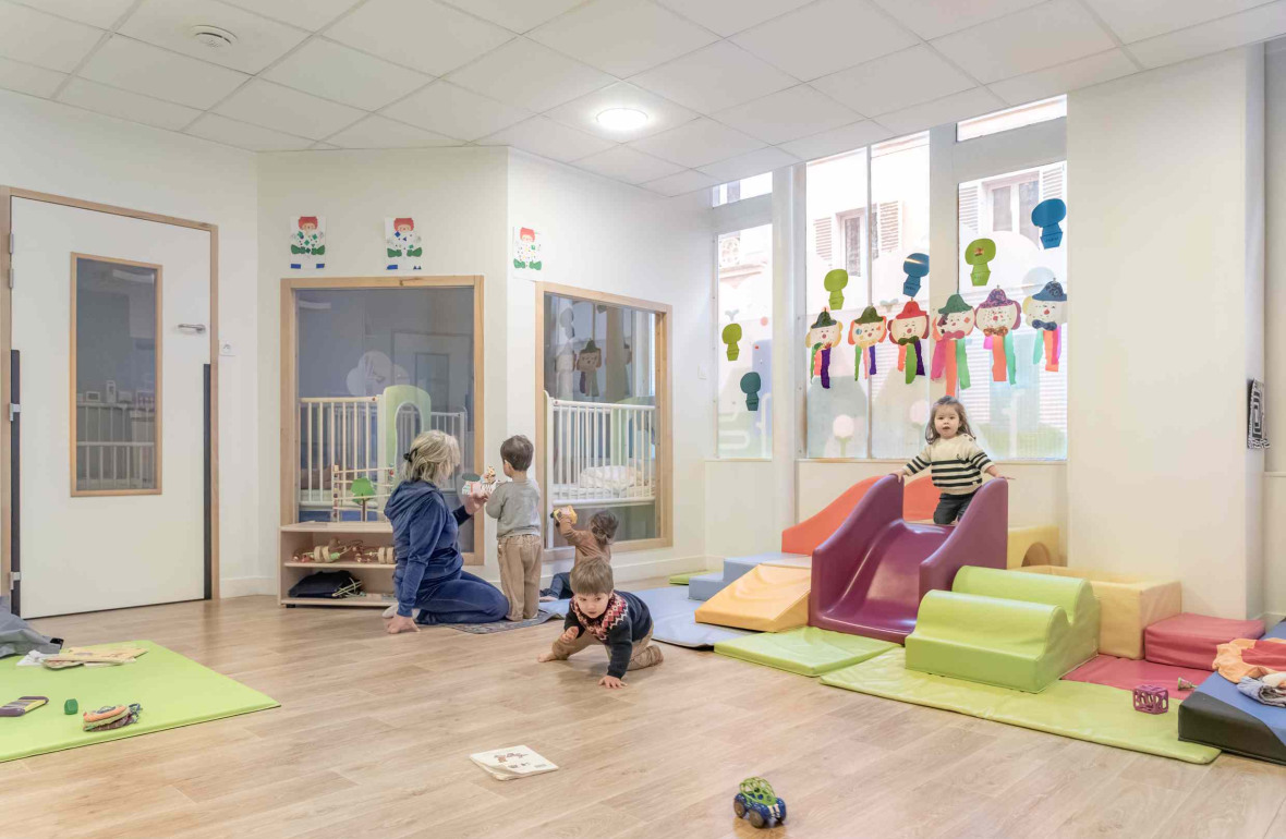 Une pro en crèche en interaction avec trois enfants 