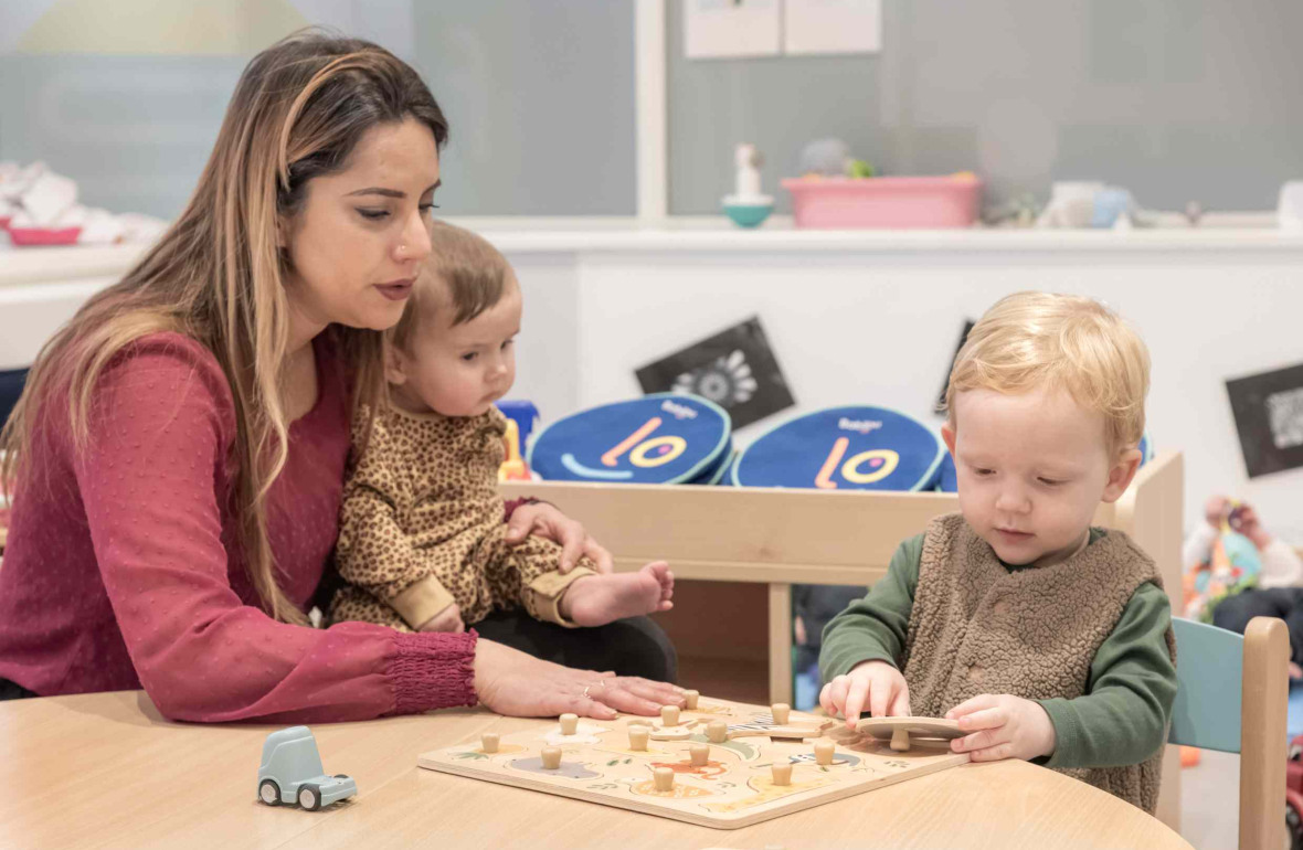 Une pro en crèche en interaction avec deux enfants 