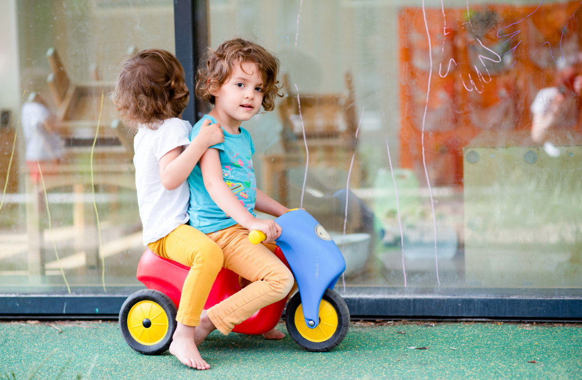 Deux petites filles jouant sur un tricycle en extérieur
