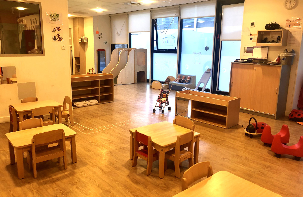 Salle d'éveil avec tables et tabourets au sein de la crèche Babilou Grenoble Schuman