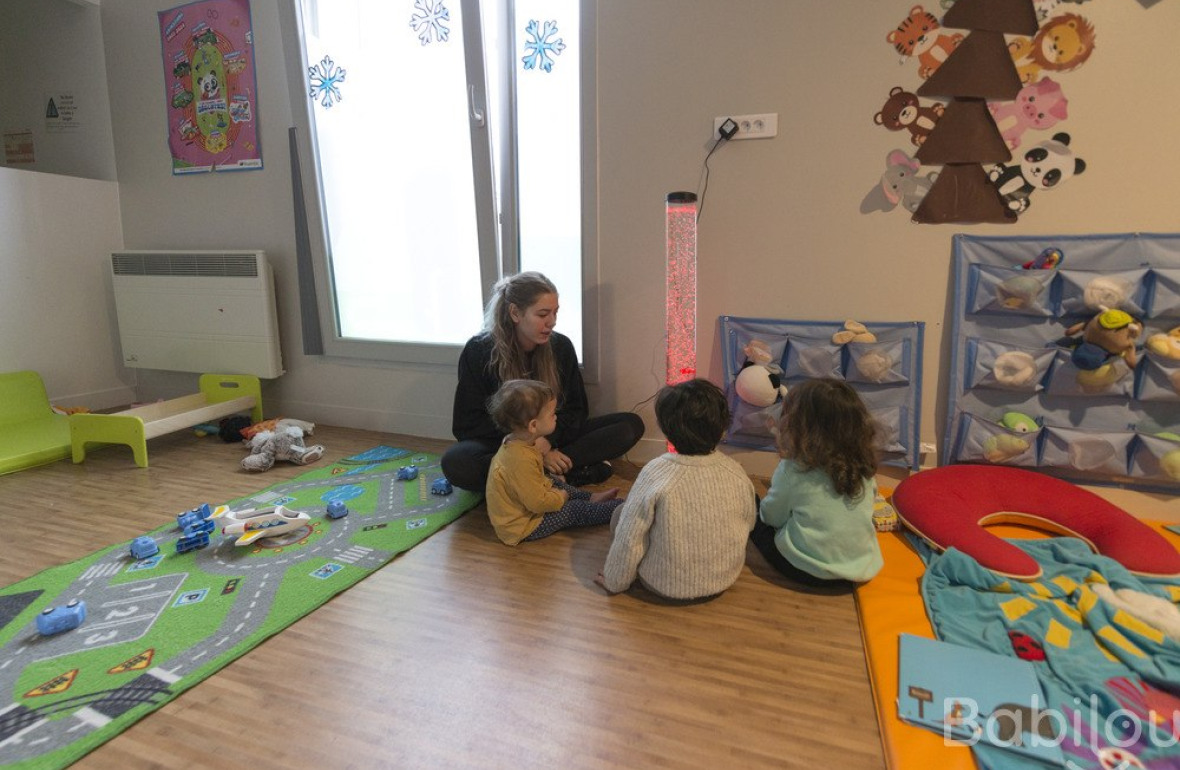 Une pro en crèche en interaction avec un groupe d'enfants 