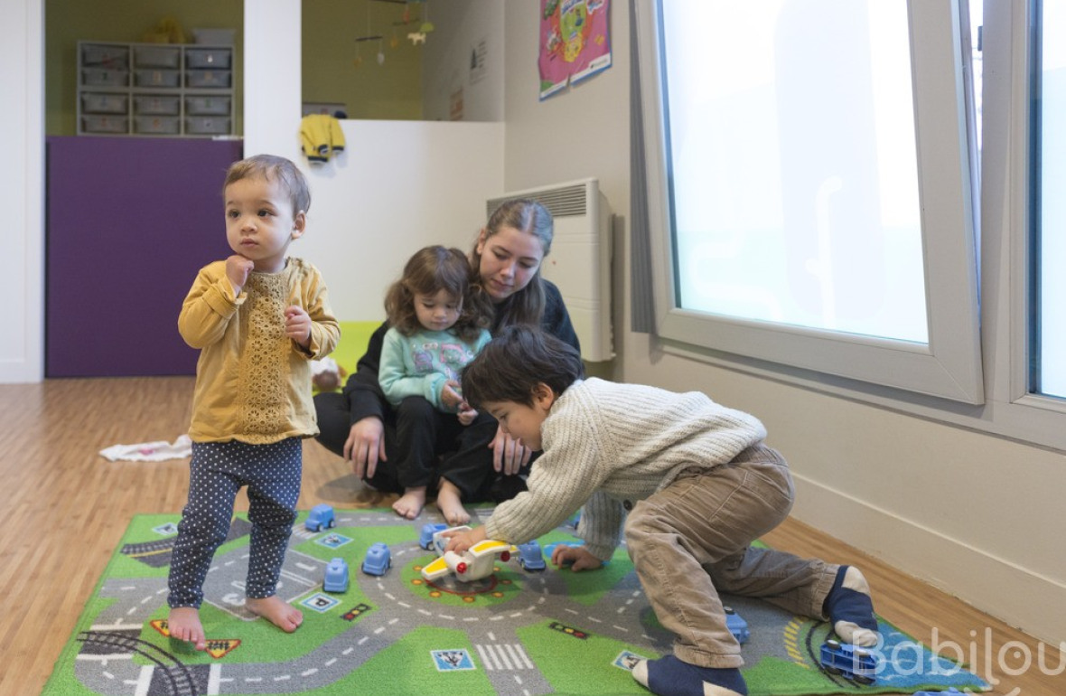 Une pro en crèche en interaction avec un groupe d'enfants