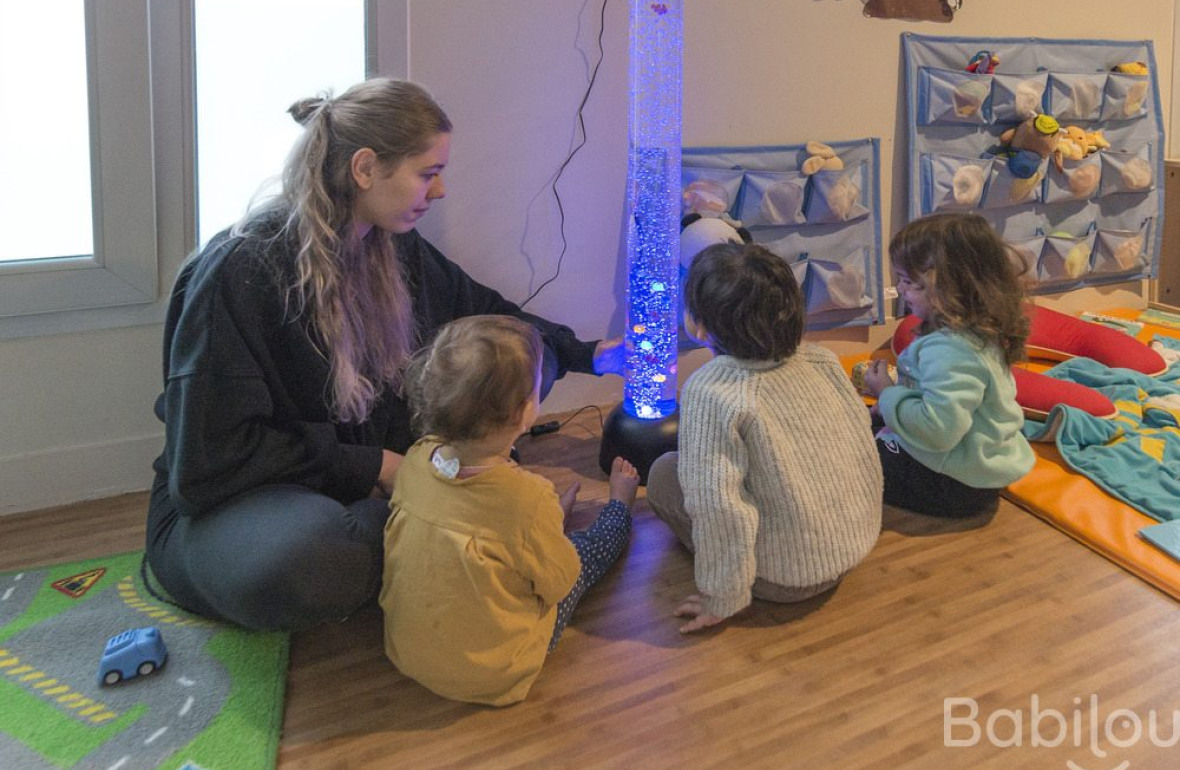 Une pro en crèche en interaction avec un groupe d'enfants 