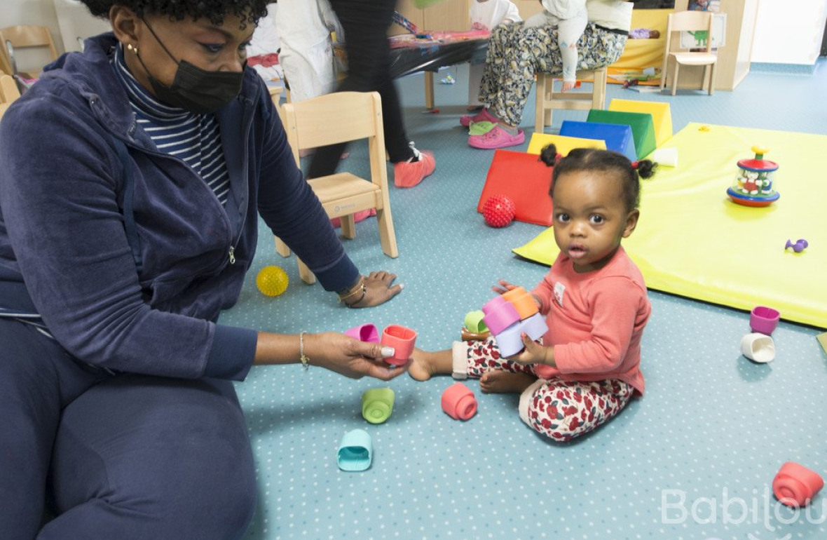 Une professionnelle en crèche qui joue avec une enfant