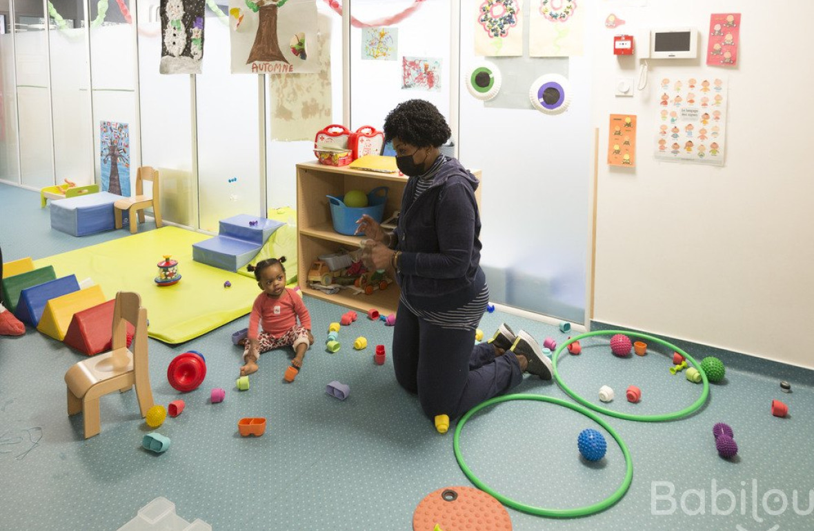 Une professionnelle en crèche qui joue avec une enfant