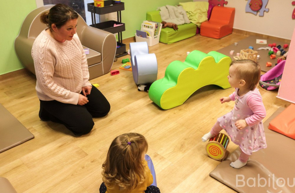 Une professionnelle en crèche qui joue avec deux enfants