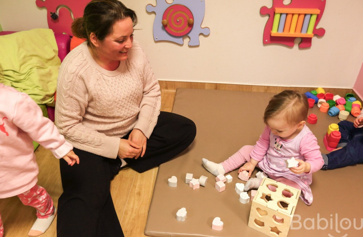 Une professionnelle en crèche Babilou qui joue avec une enfant