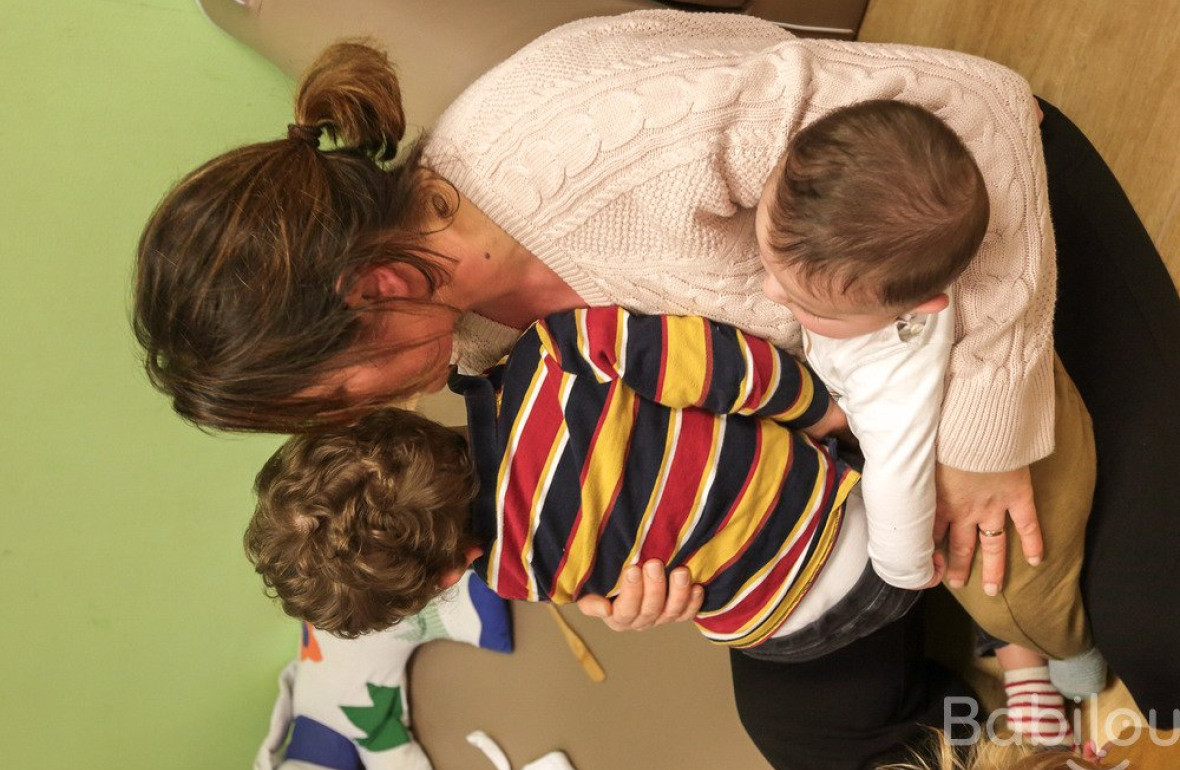 Une professionnelle en crèche avec deux enfants