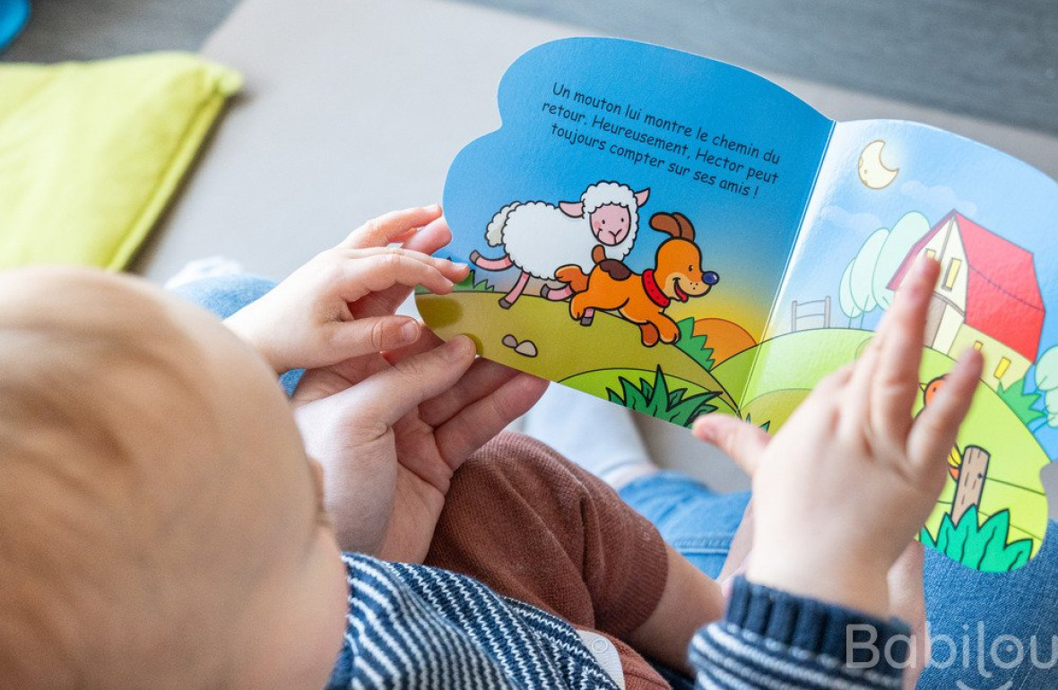 Un bébé en crèche Babilou qui regarde un livre 