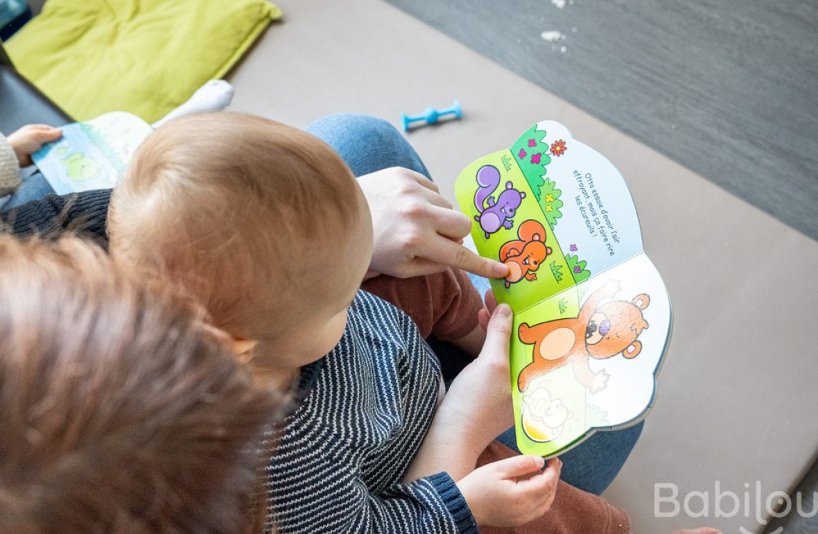 Un bébé en crèche Babilou qui regarde un livre 