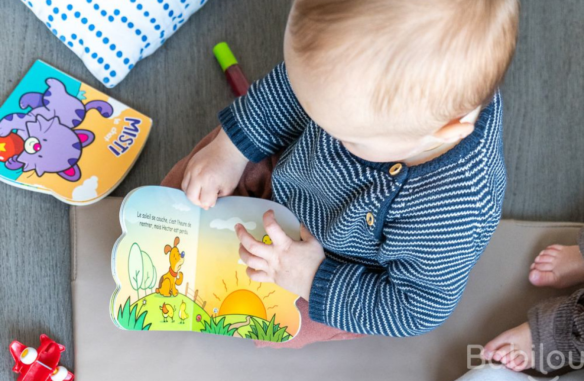 Un bébé en crèche Babilou qui regarde un livre 