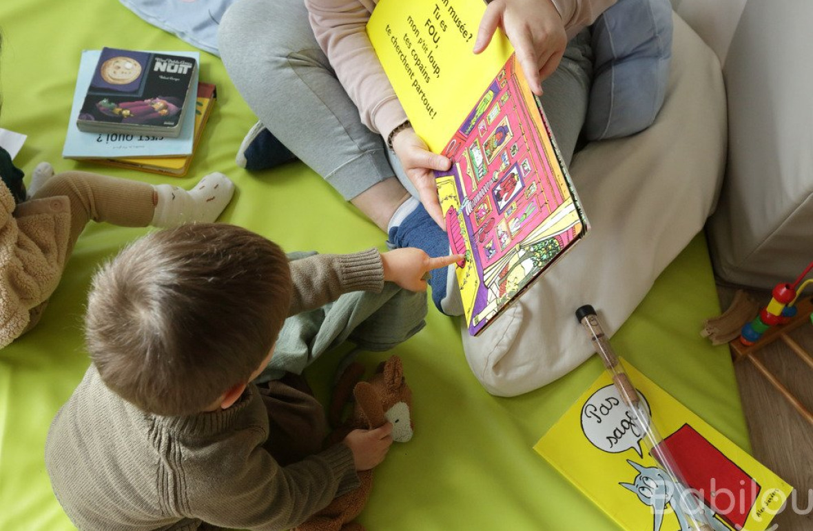 Une pro en crèche qui lit un livre à un enfant