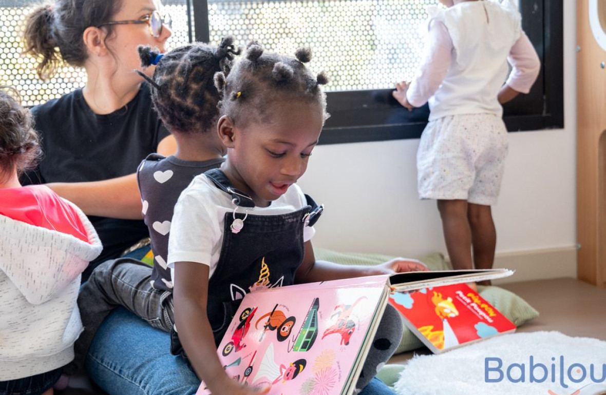 Une petite fille en crèche qui regarde un livre