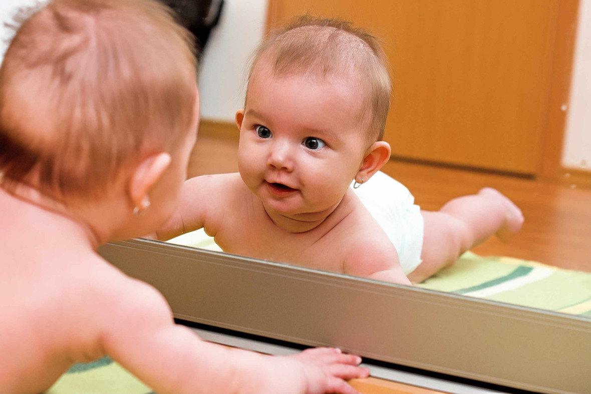 Un bébé allongé qui se regarde dans le miroir