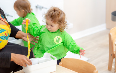 Petite fille qui joue avec un bac sensoriel rempli d'éléments naturels