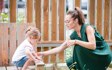 Une professionnelle de crèche avec un enfant dans un jardin