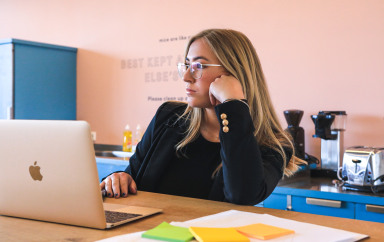 Jeune fille pensive, travaillant à domicile, devant son ordinateur portable