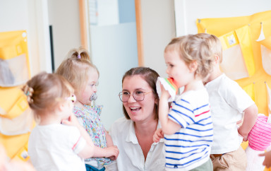 Professionnelle en crèche entourée d'enfant rigolant