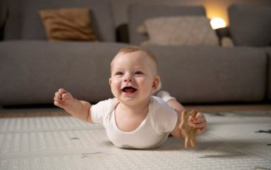 Un bébé souriant allongé au sol avec un hochet 