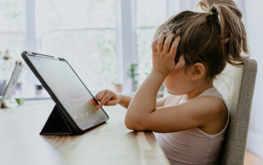 Un enfant sur une table en tain de jouer à la tablette