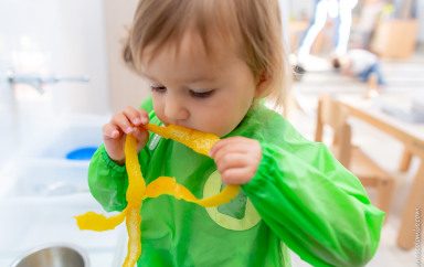 Enfant en crèche Babilou en train de goûter une écorce de citron