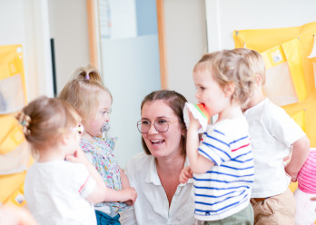 Professionnelle en crèche entourée d'enfant rigolant
