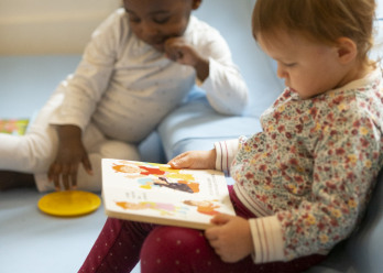 Deux enfants dont un lisant un livre au sein de la crèche