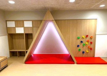 Structure en bois éclairée et mur d'escalade au sein de la crèche Babilou de Choisy-le-Roi Blanqui