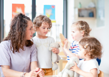 Professionnelle en crèche discutant avec un groupe d'enfants