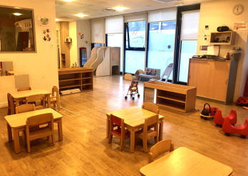 Salle d'éveil avec tables et tabourets au sein de la crèche Babilou Grenoble Schuman