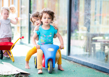 Deux enfants sur un vélo à l'extérieur de la crèche